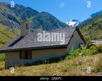 Un bellissimo scatto di una casa rurale sotto verdi colline e montagne di neve a Champagny le Haut, Francia Foto Stock