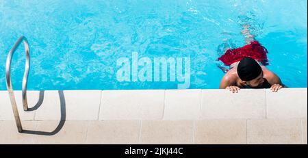 Una vista dall'alto di un uomo ispanico in piscina in una giornata di sole in Colombia Foto Stock