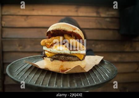 Un primo piano di un grande e succoso hamburger su un asse di legno Foto Stock