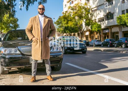 Attraente modello caucasico in piedi davanti ad una limousine auto all'aperto Foto Stock