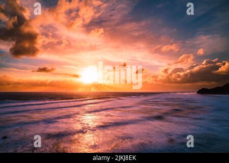 Una splendida vista panoramica del mare contro il cielo crepuscolo ad un tramonto epico, Piha Beach, Auckland, Nuova Zelanda Foto Stock