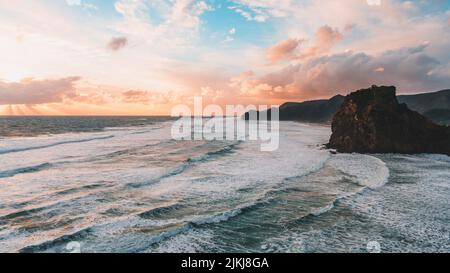 Una splendida vista panoramica della formazione rocciosa e delle montagne contro il cielo crepuscolo, Piha Beach, Auckland, Nuova Zelanda Foto Stock