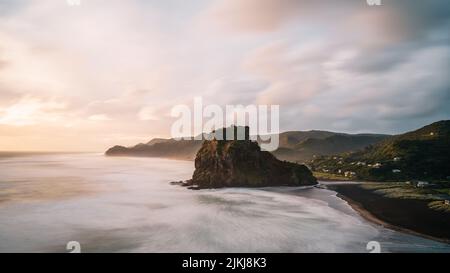 Una splendida vista panoramica della formazione rocciosa e delle montagne contro il cielo crepuscolo, Piha Beach, Auckland, Nuova Zelanda Foto Stock