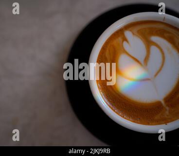 Una vista dall'alto di un caffè del sabato Cappuccino con un design sopra il latte e la luce primaverile del mattino Foto Stock