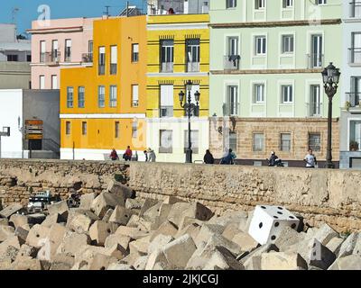 Un viale sulla spiaggia con case splendidamente colorate sullo sfondo a Cadice, Spagna Foto Stock