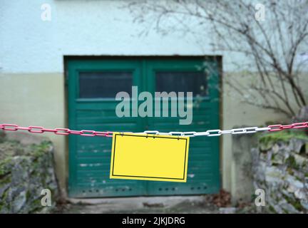 Un primo piano di un cartello bianco giallo davanti ad un cancello Foto Stock