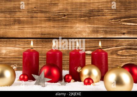 Candele rosse con palle di Natale su uno sfondo di legno sulla neve Foto Stock