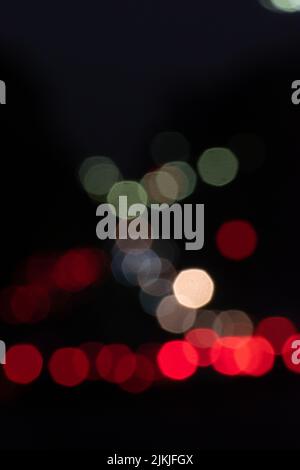 Una foto verticale di luci bokeh colorate su sfondo scuro Foto Stock