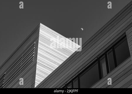 Un'immagine in scala di grigi, ad angolo basso di un edificio contro il cielo con la Luna Foto Stock