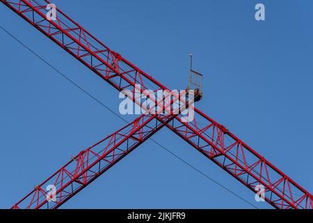 Un tiro a basso angolo di una grande gru da costruzione rossa contro un cielo blu Foto Stock