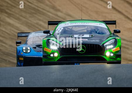 Un tiro a basso angolo di una Mercedes-AMG GT3 nera e di una Porsche 911 GT3 RSR blu durante la gara nel British GT Championship, Foto Stock