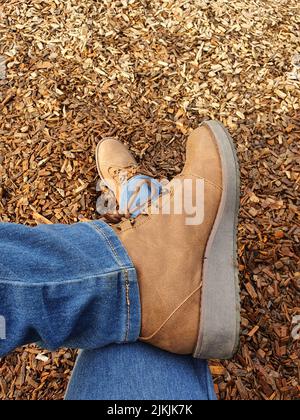 Un tiro verticale ad angolo alto delle gambe incrociate di una donna viaggiatore in scarpe da trekking Foto Stock