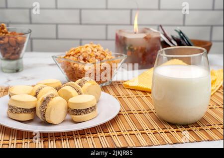 Un primo piano di un bicchiere di latte accanto ad alcuni biscotti e dolci sul tavolo. Foto Stock