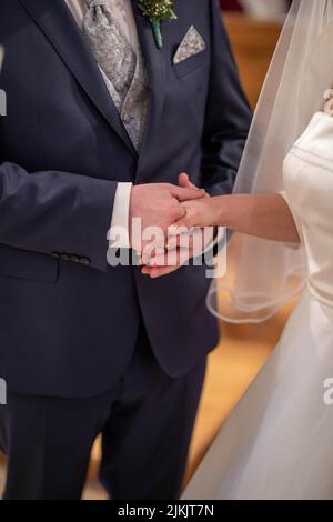 Un primo piano verticale di uno sposo e di una sposa che tiene le mani alla cerimonia nuziale Foto Stock