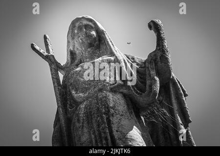 Una vista dall'angolo basso di una scultura femminile con una luce sullo sfondo Foto Stock