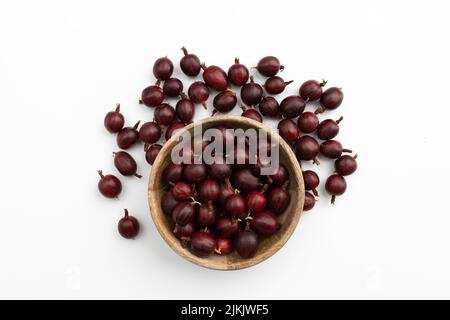 gooseberry rosso fresco in ciotola di legno isolato su sfondo bianco, vista dall'alto Foto Stock