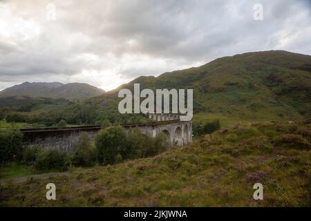 Una vista panoramica del Viadotto di Glenfinnan sulle verdi colline in una giornata nuvolosa Foto Stock