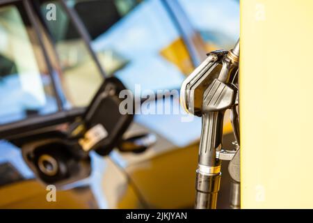 Ugello del combustibile in una stazione di servizio con tappo del serbatoio del combustibile su un'auto Foto Stock