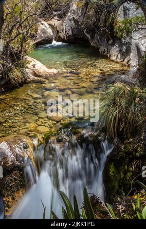 Una bella vista panoramica di un piccolo laghetto e cascate sulla montagna in piena luce del sole Foto Stock