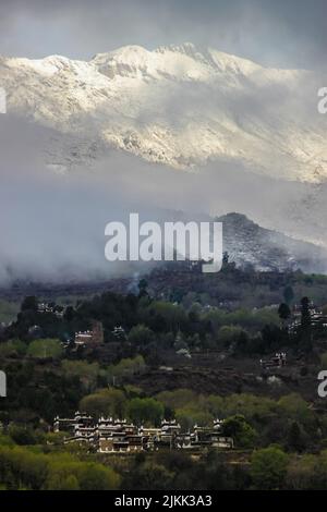 Un bellissimo scatto delle case tibetane di Jiarong su una montagna innevata nel villaggio tibetano di Zhongli, Cina Foto Stock