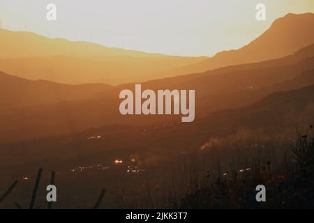 Una silhouette di un tempo nebbia sulle montagne durante il tramonto Foto Stock
