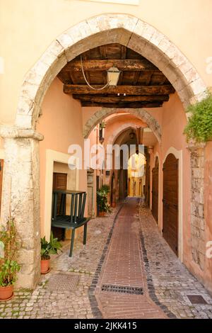 Uno scatto verticale di uno stretto corridoio acciottolato tra vecchi edifici medievali. Foto Stock