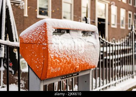 Cassetta postale verde arancione olandese coperta di neve nelle strade del quartiere di Utrecht Lombok. Foto Stock