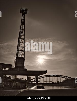 Una scala di grigi verticale di una gru da cantiere lungo il fiume meno a Francoforte sul meno, in Germania Foto Stock