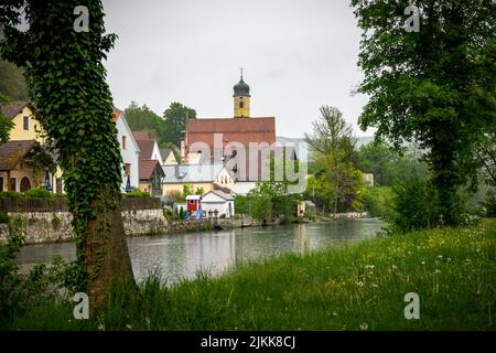 Vista idilliaca del villaggio di Markt Essing in Baviera, Germania, con il fiume Altmühl e alte scogliere in una giornata di sole in primavera Foto Stock