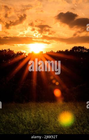 Una vista panoramica del luminoso tramonto che splende su un campo agricolo in campagna Foto Stock