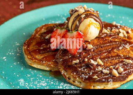 Un primo piano di deliziosi pancake con gelato e fragole Foto Stock