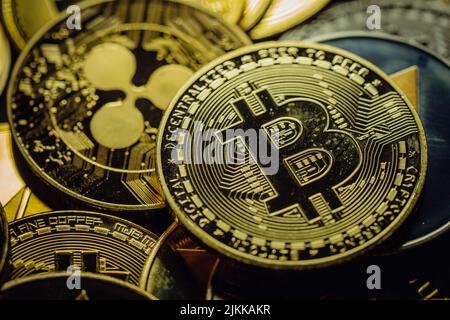 Primo piano di un Bitcoin d'oro in una pila, tra le altre varie criptovalute digitali. Foto Stock