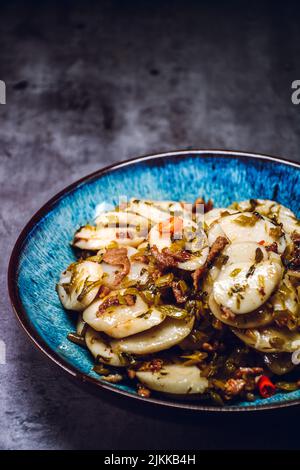 Un colpo verticale di una porzione di torta di riso fritto con maiale grattugiato e verdure salate su un piatto blu Foto Stock