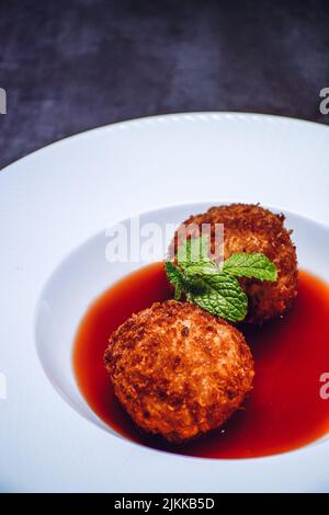 Un primo piano verticale di due palline di riso Arancini sul piatto bianco Foto Stock