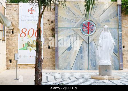 Nazareth, Israele - 21 settembre 2017: Statua della Vergine Maria accanto alla Basilica dell'Annunciazione. Il testo verticale greco sul muro in backgrou Foto Stock