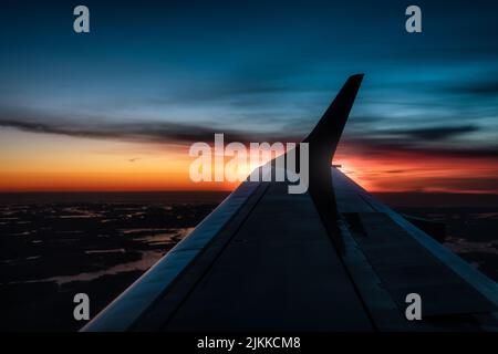 L'ala di un aereo che sorvola la Svezia durante il tramonto Foto Stock