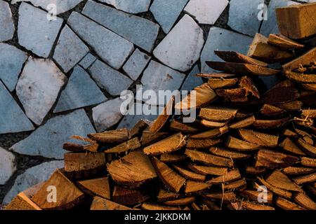 Un primo piano di un mucchio di pezzi di legno contro il muro di mosaico in pietra Foto Stock