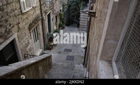 Un alto angolo di scale di pietra che scendono verso un cortile contro vecchie case a Dubrovnik, Croazia Foto Stock