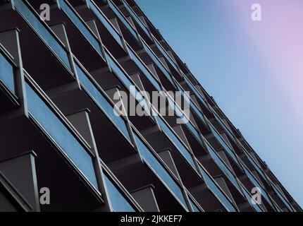 Un basso angolo di un edificio in vetro riflettente sotto un cielo blu viola Foto Stock