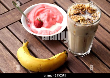 Un primo piano di gelato Strawberry piatto, banana e caffè ghiacciato con noci su un tavolo di legno Foto Stock