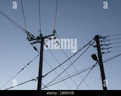 Un colpo di pali di servizio e cavi elettrici e il cielo blu Foto Stock