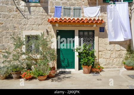 Una casa carina con una porta verde decorata con piante e lavanderia appeso a una corda a Spalato, Croazia Foto Stock