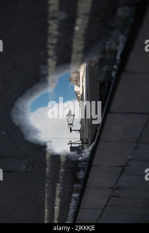 Il riflesso di un lampione su una piccola pozzanghera sulla strada Foto Stock
