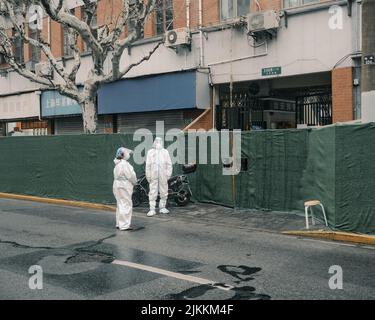 Un operatore sanitario in tute hazmat garantire che i residenti non lasciare i loro composti a Shanghai, Cina Foto Stock