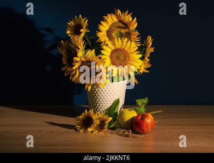 Una vista di mazzo di girasoli in vaso vicino alle mele sul tavolo sullo sfondo dell'ombra Foto Stock