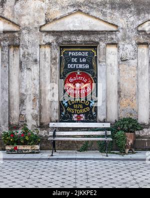 Un primo piano di una panca di legno nelle strade di fronte a un poster su un muro in Argentina Foto Stock