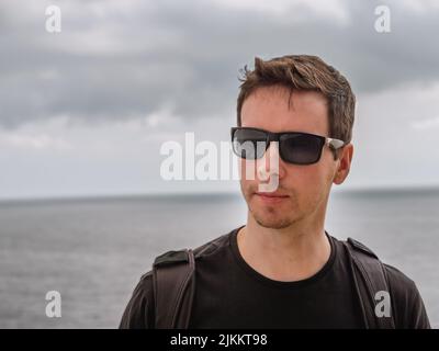 Un primo piano di un uomo su una nave da crociera con l'oceano sullo sfondo Foto Stock