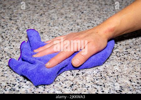 Pulire a mano una superficie di granito con uno straccio Foto Stock