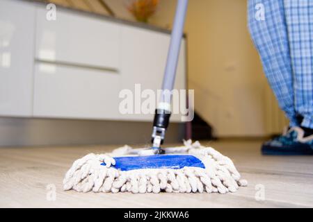 Donna che pulisce il pavimento di una casa con un mop Foto Stock