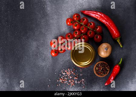 Salsa di pomodoro dolce piccante con aglio, pepe ed erbe in vasetti di vetro. Pomodori in scatola in succo di pomodoro Foto Stock